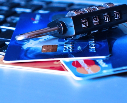 Eine Nahaufnahme eines Kombinationsvorhängeschlosses, das über einer Laptop-Tastatur auf Kreditkarten liegt. Es symbolisiert die Online-Sicherheit und den Schutz von Finanzinformationen inmitten von Bedenken wie gestohlenen Zugangsdaten oder einem PayPal-Datenleck.